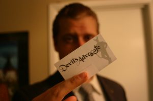 Man holding business card that says Devil's Advocate