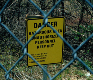 A photo of a yellow sign through a chainlink fence.