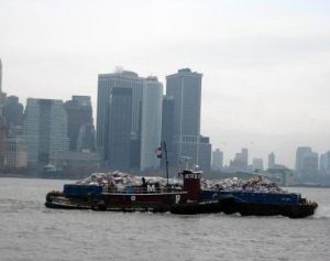 Photo of a barge in the water with a city skyline in the background