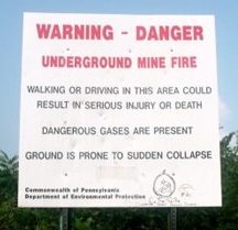 Photograph of a red and black sign warning of underground coal mine fires