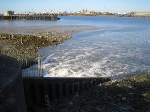 A photo of a sewage outfall: effluent is entering a river.