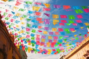 A bunch of color tissue paper hanging over the street.