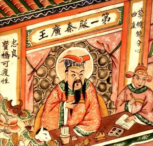Close-up of the king of the first court of hell. He is dressed like a Chinese emperor, and strokes his long beard. To the right, his assistant is dressed like an official and holds his brush and booklet at the ready for notetaking. In the lefthand corner are an ox-headed and horse-headed hell guard
